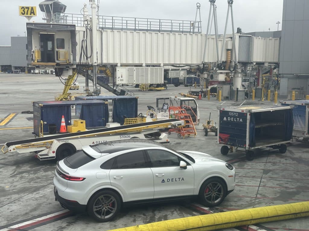 Delta-branded Porsche Cayenne vehicle parked at LAX Gate 37A for VIP ground transfer service.