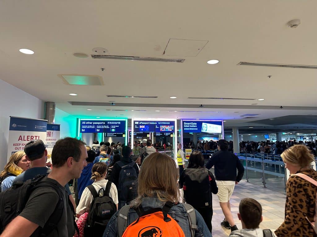 Travelers in queue at Brisbane International Airport arrivals using ePassport and SmartGate immigration lanes in 2025.