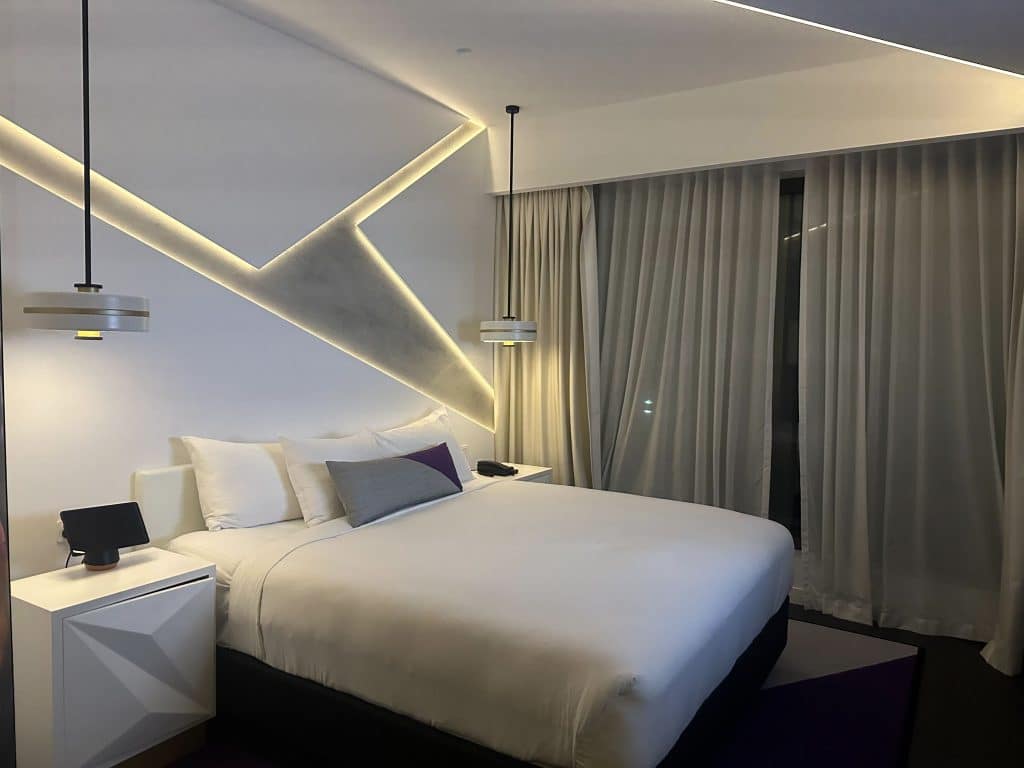 Modern king bedroom at Hotel X Brisbane with angular lighting and purple accent