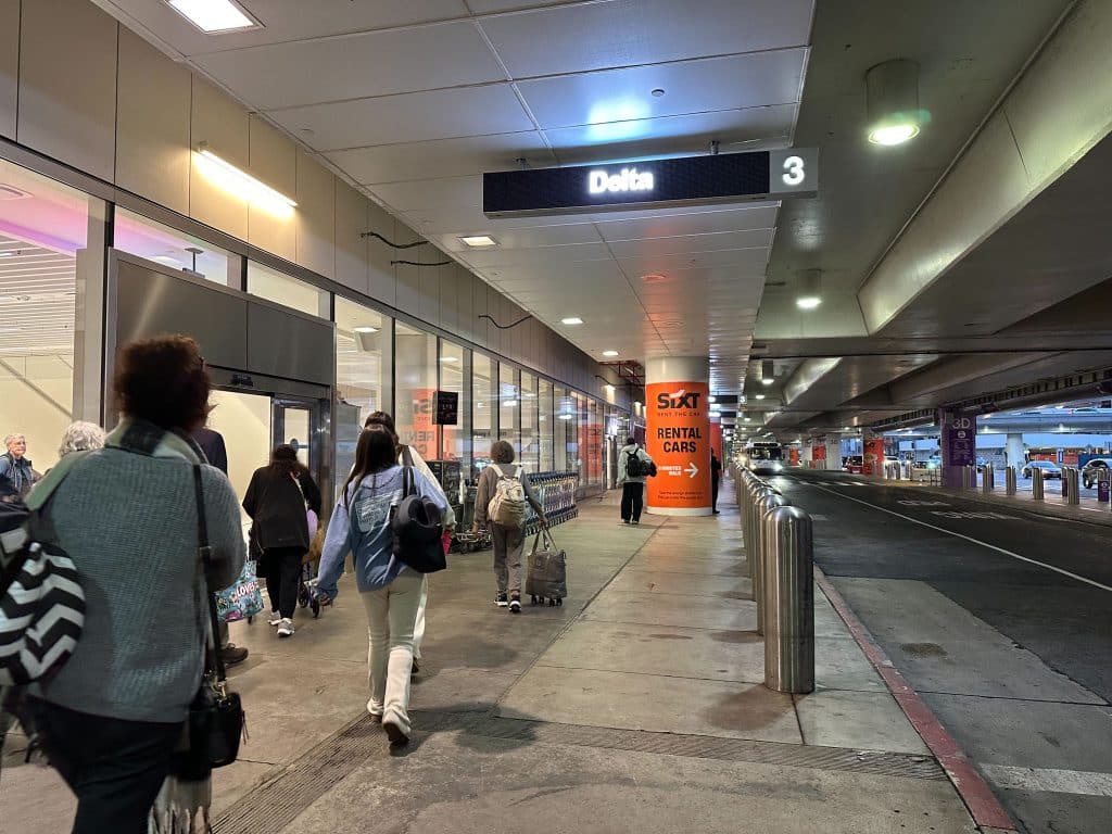 LAX Delta Terminal 3 exterior with entrance signage and Sixt rental car banner.