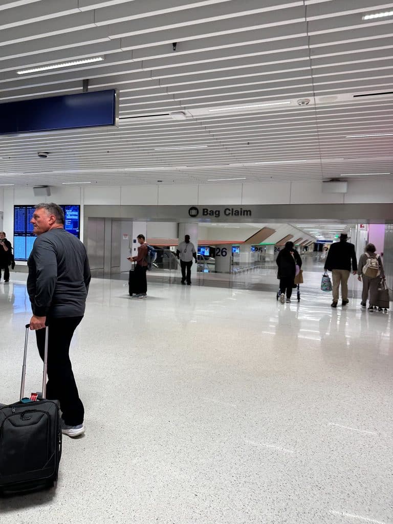 Travelers walking toward baggage claim area in LAX Terminal 3 after clearing customs.