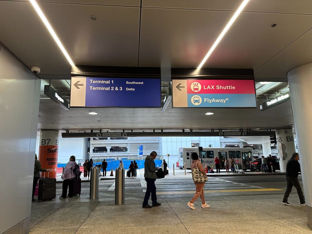 LAX terminal signage showing directions to Southwest, Delta terminals, and FlyAway shuttle buses.